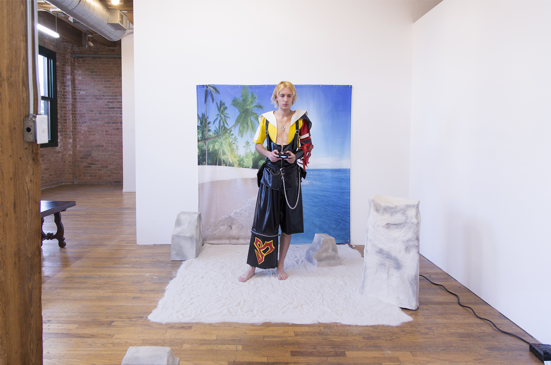 Frontal shot of Jesse dressed in cosplay playing video games on an artificial beach set